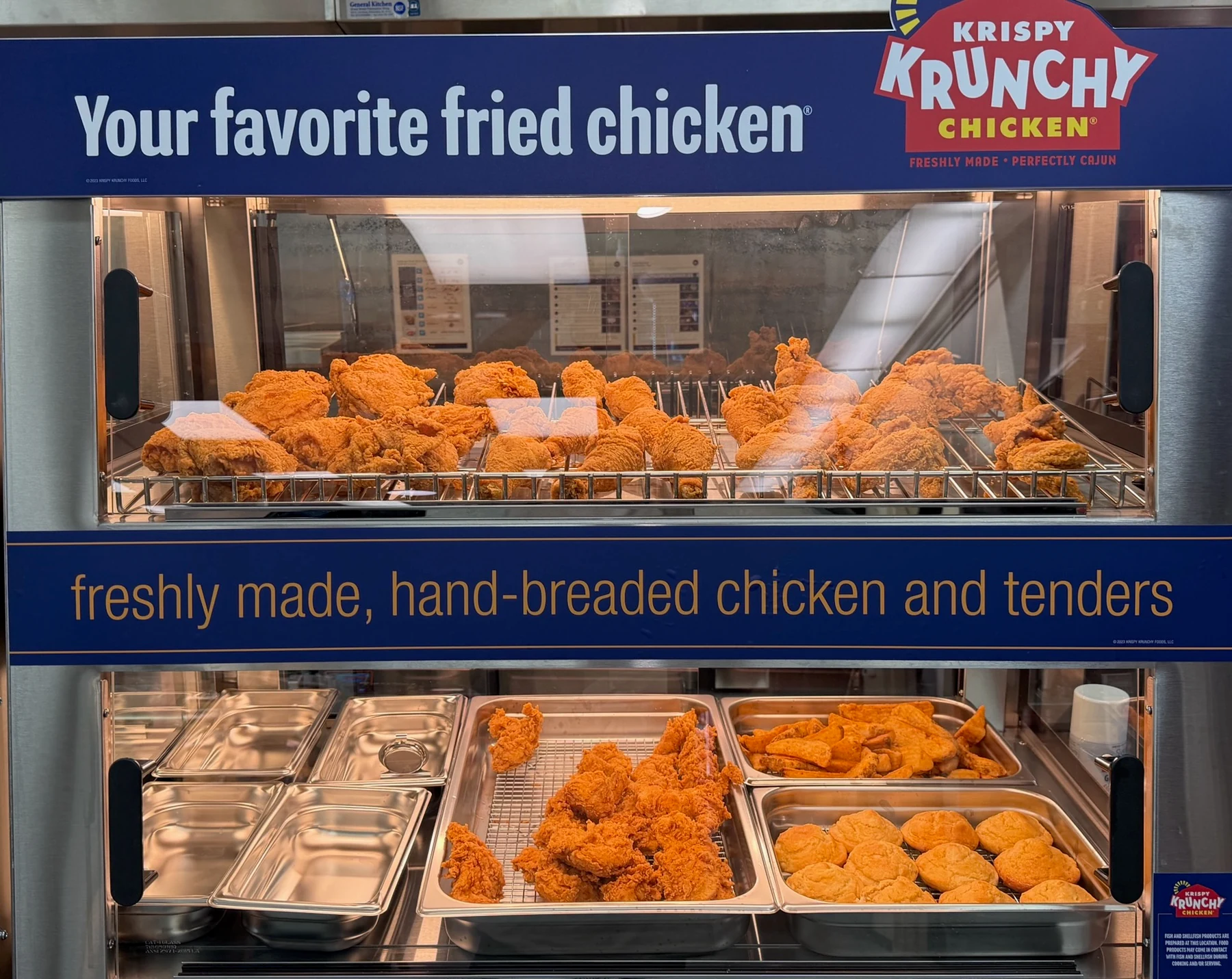 Krispy Krunchy Chicken hot food display with fried chicken, tenders, and biscuits inside Eagle Smoke & Convenience Shop